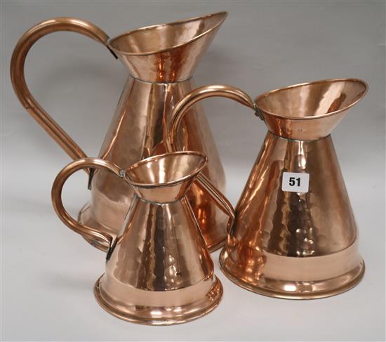 A set of three graduated copper jugs